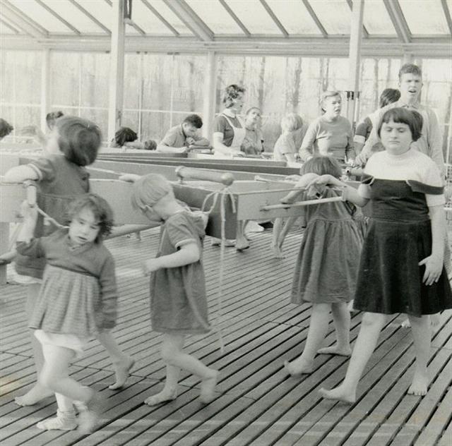 Kinderen leren lopen in een tredmolen in de wintertuin van de Willem van den Berghstichting.